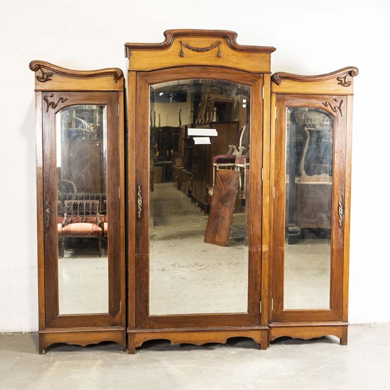 Ropero art nouveau (en tres partes), con tres puertas de espejos biselados y con molduras talladas. Laterales fisurados, detalles en la madera y en el lustre. Algún orificio de polilla en la trasera. - Medidas: 246 x 46 x 235cm