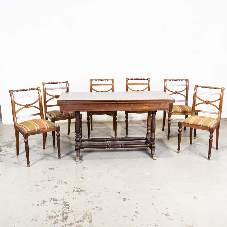 Mesa libro inglesa y seis sillas Sheraton. Sillas con asientos tapizados. Tapizados con averías (para retapizar). Alguna silla floja y una pata suelta. Tapa rayada y detalles en el lustre. Detalles en la tapa abierta. - Medidas: 147 x 63 x 80cm