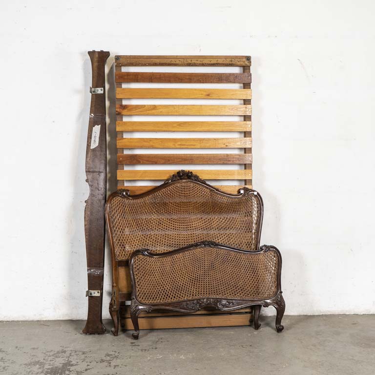 Cama de una plaza francesa, esterillada y tallada. Piecera con doble esterillado. Respaldo con avería, detalles en la madera y en el lustre. No se armó, se remata a la vista. - Medidas: Respaldo 109 x 115, largueros 191cm