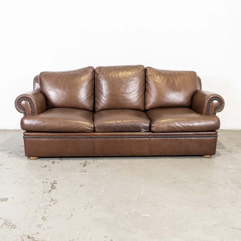 Sofá cama, de tres cuerpos, tapizado en cuero marrón con tachas . Almohadones en respaldo y asiento. Estructura de la cama en metal y madera. Buen estado general. - Medidas: 207x85x85cm
