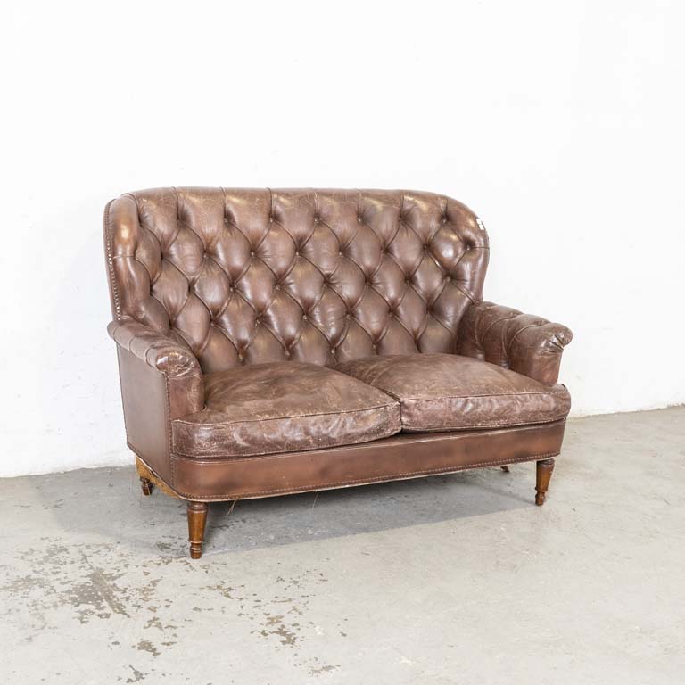 Sofá de dos cuerpos inglés, con respaldo capitoneado y almohadones en el asiento. Para retapizar, tapizado con desgaste y cuarteado. Detalles en el lustre. - Medidas: 144x66x96cm