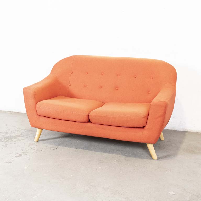 Sofá de dos cuerpos color anaranjado, tapizado en tela. Con patas de madera, almohadones en los asientos y botones en el respaldo. Falta botón y tapizado descolorido. - Medidas: 145 x 63 x 86cm