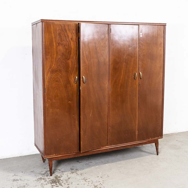 Ropero americano, de cuatro puertas. Interior con cajones y espejo. Detalles en el lustre, interior con avería en el enchapado. Pata frontal inclinada y clavada, detalles en el lustre. Trasera con averías. - Medidas: 167x53x182cm