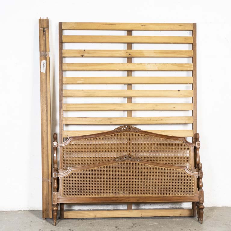 Cama Luis XVI, de dos plazas. Tallada y esterillada (piecera con doble esterillado). Respaldo con avería en la madera y detalles en el lustre. No se armó, se remata a la vista. - Medidas: 151 x 100, largueros: 203cm