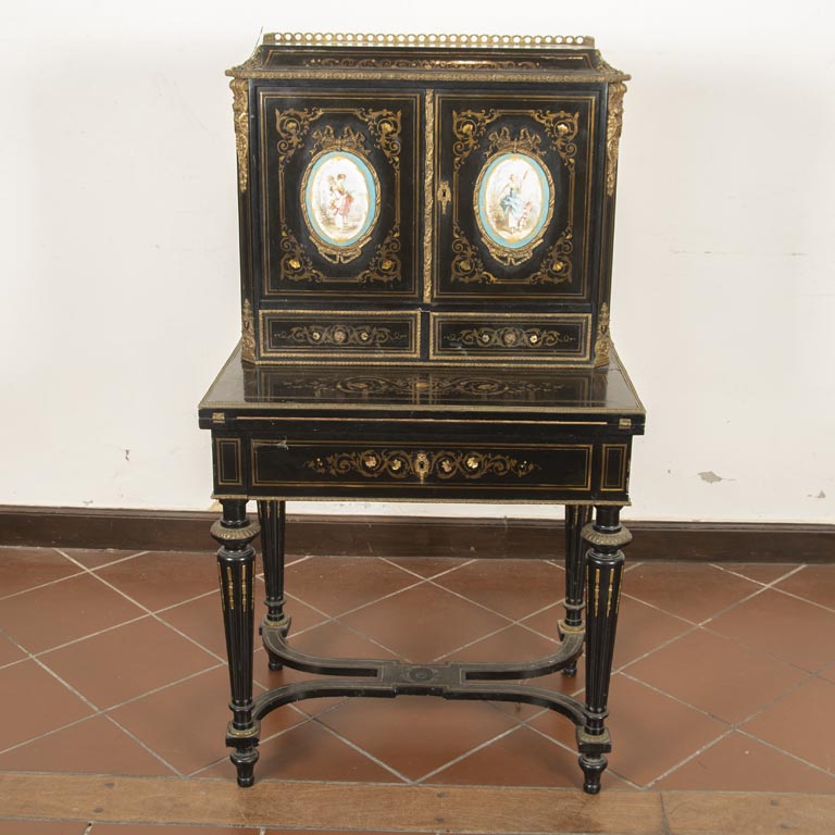 Bonheur ju jour Napoleón III, en madera ebonizada, aplicaciones de bronce y nácar, 1 cajón y tapa de volcar; alzada de 2 puertas con medallones ovales de porcelana y 2 cajones - Medidas: 74x50x133cm