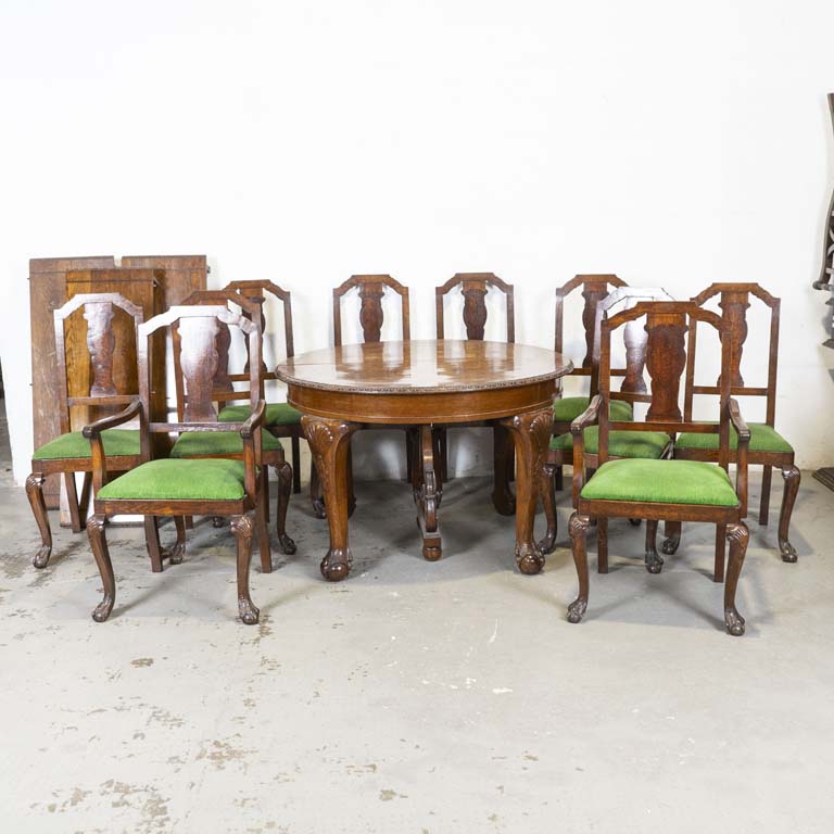 Mesa de comedor circular reina Ana, en roble, con: marqueterie en la tapa, tres tablas, dos butacas y ocho sillas. Asientos tapizados en pana verde y respaldos con marqueterie. Detalles en el lustre. Alguna tabla con detalles en la madera. - Medidas: 116 x 78cm