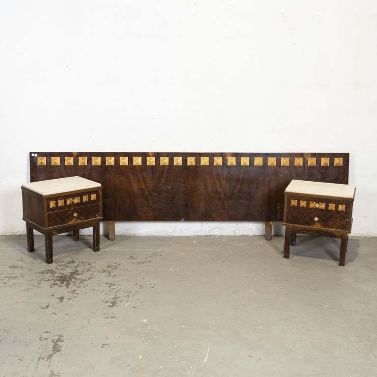 Respaldo de dos plazas y dos mesas de luz. Mesitas con: tapa de mármol y dos cajones cada una. Mármol con avería, polillas en la trasera, detalles y manchas en el enchapado. - Medidas: 265x74cm