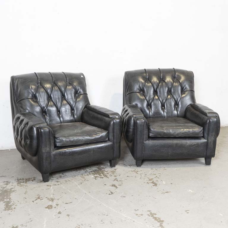 Par de sillones tapizados en cuerina negra, respaldos y laterales capitoneados. Con almohadones en los asientos. Mínimos detalles en los tapizados (para limpiar). - Medidas: 80x80x83cm