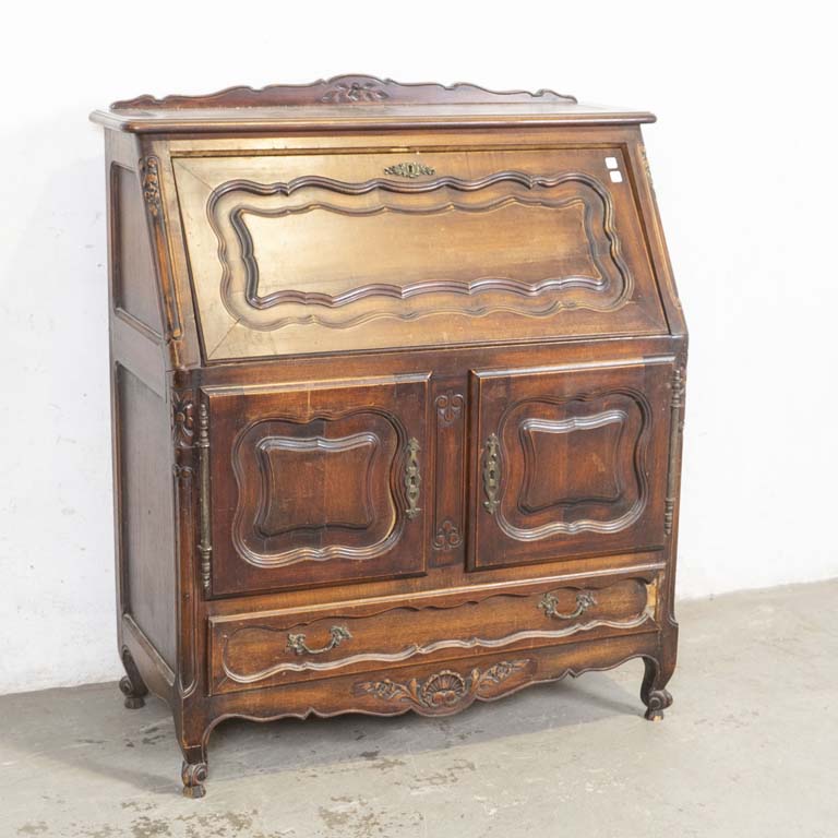 Secretaire provenzal tallado, con tres puertas y un cajón. Faltante en el frente del cajón. Interior del escritorio con avería en la puerta y enchapado levantado. Detalles en la madera, polillas en la trasera y detalles en l lustre. - Medidas: 94x46x116cm