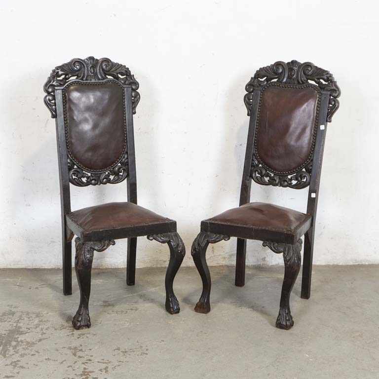 Par de sillas renacimiento, con asientos y respaldos tapizados en cuerina. Averías en las molduras de las patas, tapizados sueltos (faltan tachas). Detalles en la madera y en el lustre. - Medidas: 45 x 43 x 110cm
